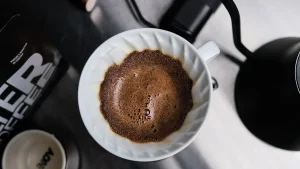 V60 드리퍼에서 갓 부은 물에 원두가 부풀어 오르는 블룸(blooming) 장면 — 탈가스 중 방출되는 CO2